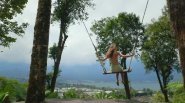 Salıncakta Sallanan Kız Dağların Manzarası ve Küçük Kasaba. Güzel beyaz kız Bali, Endonezya 'da eğleniyor ve manzaranın tadını çıkarıyor. Seyahat ve Turizm Konsepti
