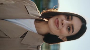 Dikey video. Neşeli Bayan Kameraya Gülümseyen ve Poz Veren. Kendine güvenen genç kız dışarıda dikilirken kameraya bakıyor. İnsanlar Konsepti