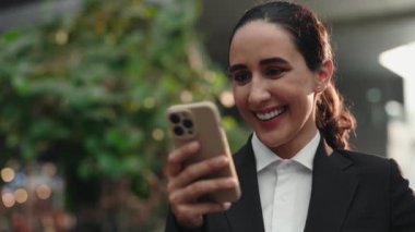 Pozitif Kadın, Smartphone 'dan komik video alıyor Ofis Binası' nda dikiliyor. Güzel girişimci cep telefonundan havalı mesajlar okuyor ve tadını çıkarıyor. Halk ve Teknoloji Konsepti