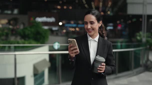 年轻迷人的女商人在商务中心走来走去 在电话上工作 手里拿着咖啡 美丽快乐的律师去工作 发短信给客户 人与技术概念 — 图库视频影像