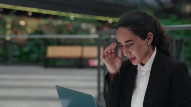 İş kadını, iş merkezinde otururken dizüstü bilgisayarına odaklanmak, kafasına masaj yapmak için çabalıyor. Stresli Profesyonel Kadın Ofiste İşten Sonra Baş Ağrısı Hissediyor