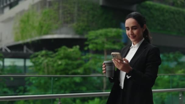スマートフォンでクライアントに相談する忙しい起業家 コーヒーブレイクから歩いている間 オフィスビルに行く間 顧客とポジティブな女性チャット 人と技術のコンセプト — ストック動画