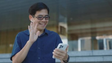 Çevrimiçi Öğretim Üretim Üniformalı Yakışıklı Gülümseyen Öğretmen Smartphone kullanarak öğrencileri selamlıyor. İnternetteki Video Toplantısı 'nda müşterilere el sallayan yaşlı adam. Halk ve Teknoloji Konsepti