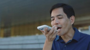 Olumlu Olgun Adam dışarıda hoparlörden ses tanıma mesajı kaydediyor. Kıdemli Yönetici Smartphone Outdoor 'da Sanal Asistan Uygulamasını Kullanıyor. Dijital AI Mobil Yardım Tekniği