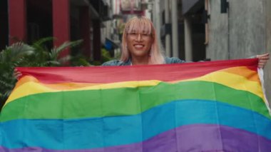 Gülümseyen Transseksüel Adam ayakta ve LGBT bayrağı taşıyor. Hoş Giyimli Eşcinsel Adam Gökkuşağı Bayrağını Kameraya Gösteriyor. LGBT Topluluğunun Onur Desteği. LGBT İnsanlar Kavramı