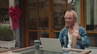 Pembe saçlı LGBT çalışanı dışarıda çalışan arkadaşlarını bilgisayar kullanarak arıyor. Transseksüel erkek hareketi dizüstü bilgisayar ekranına. Gurur Halkı ve Teknoloji Konsepti