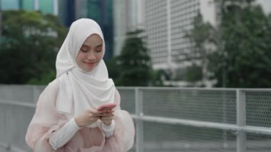 Hijab 'daki Genç Güzel Kız Şehirde Gezinirken Arkadaşlarına Sosyal ağlar' dan mesaj atıyor. Cazibeli Müslüman Kız Dışarı Çıkıyor, Konuşuyor, Cep Telefonu Kullanıyor. Halk ve Teknoloji Konsepti