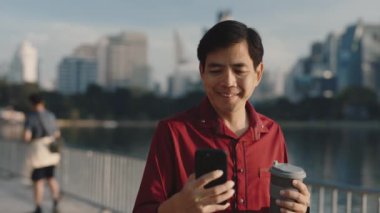 Neşeli kıdemli adam kahve molasında dışarıda duruyor ve akıllı telefonda komik videolar izliyor. Yaşlı patron cep telefonunu kullanarak gölün yakınında geziyor. Halk ve Teknoloji Konsepti