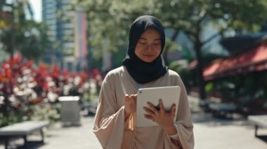 Dışarıda Başörtüsü Giyip Arkadaşlarıyla Tablet 'te Mesajlaşan Mutlu Genç Kız. Güzel Müslüman Kadın Sokaklara Çıkıyor, Sohbet ediyor, Not Yazıyor. Halk ve Teknoloji Konsepti
