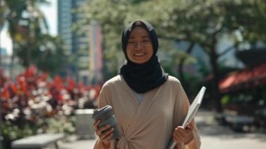 İşten Eve Dizüstü bilgisayar ve kahve taşıyarak, Geleneksel Giysiler ve Başörtüsü Giyerek Giden Genç Kadın. Pozitif Müslüman Kız Eve Gidiyor Bilgisayarı ve Sıcak İçeceği Tutuyor