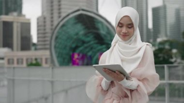 Geleneksel tesettürde Genç Müslüman Güzel Bayan Dışarıda dururken Tablet Cihazı kullanıyor. Çekici İslami Kız Tıklama ve Dijital Gadget Kaydırma, İnternet 'te Haberler Okuma