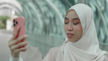 Zarif İslamcı Kadın, Smartphone, Selamlar ve Gülümsemeler Üzerine Bir Video Görüşmesi Yapıyor. Zarif Müslüman Kız İş Arkadaşlarıyla Çevrimiçi Sohbet ve Çalışma Fikirleri Paylaşımı aracılığıyla Konferans Yapıyor