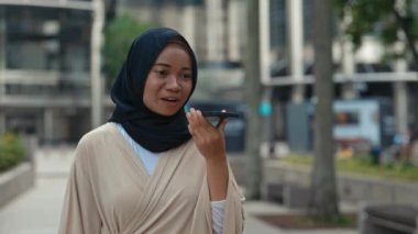 Çekici İslamcı Kadın dışarı çıkıyor ve akıllı telefondan sesli mesaj bırakıyor. Dışarıda yürürken hoparlörde konuşan Müslüman kadın. Halk ve Teknoloji Konsepti