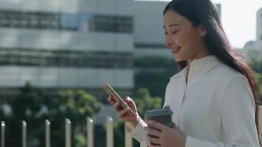 Charming Happy Student Walking Home After University ve Smartphone, Scrolling Aps Out 'un yan görüntüsü. Pozitif Kadın Yönetici İş Yeri 'ne Gidiyor ve İş Arkadaşlarıyla Mesajlaşıyor