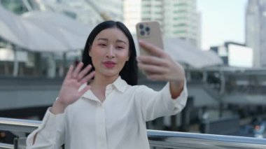 Genç Güzel Asyalı Menajer Kız, Yeni Bir İş Bulma Konferansında Patronu Karşılıyor. Güzel Olumlu Kadın Sokakta Duruyor ve Müşterilerle Görüntülü Konuşuyor, Çevrimiçi Çalışıyor