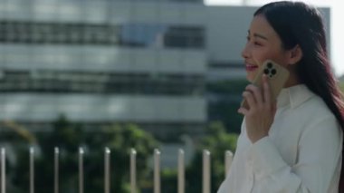Dışarıda yürürken müşterilerle telefonda konuşan çekici bir ofis kadını. Neşeli genç bayan cep telefonunu tutuyor, açık havada bir telefon görüşmesi yapıyor. Halk ve Teknoloji Konsepti