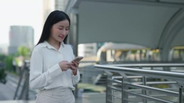 Sokakta Duran Çekici Asyalı Kız Heyecanlı Çevrimiçi Kazanan Akıllı Telefon 'da İyi Haberler Aldı. Şok Olan Genç Kadın Telefonu Tutuyor, İşi Kabul Etmeyi Kutluyor