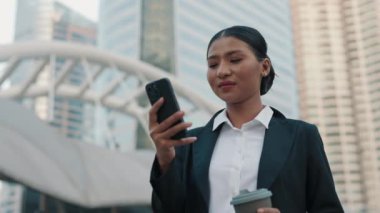 Resmi Giyimli Kız Dışarıda Duruyor ve Cep Telefonunu Kahve Molasında Çalışmak İçin Kullanıyor. Çekici bir Asyalı ofis. Telefonunu açık havada kullanan bir kadın. Halk ve Teknoloji Konsepti