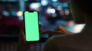Chroma Key ile Genç Kız Tutucu Smartphone 'un Gece Kenti Caddesi' ndeki Sosyal Medya İçeriği 'nin kapanışı. Yeşil Ekranlı Dokunmatik Cep Telefonu kullanan Kadın. Teknoloji İçeriği