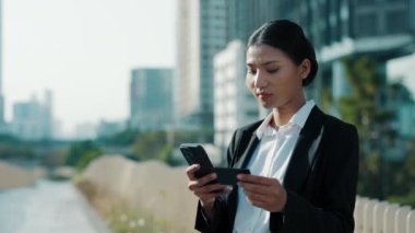 Charming Business Lady dışarıda banka kartı ve not numarasıyla Smartphone ile bekliyor. Çevrimiçi Çok Meşgul Asyalı Kız İnternetten Cep Telefonu ile Bir İnternet Dükkanı. Halk ve Teknoloji Konsepti