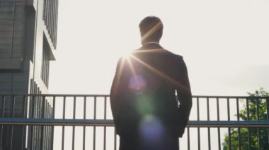 Genç yakışıklı iş adamı güneşli bir günde şehir merkezinde Köprü 'de dikiliyor, Etrafa bakıyor. Resmi Takım Elbiseli Sakallı Adam Etraftaki Her şeye Bakar. İnsanlar Konsepti