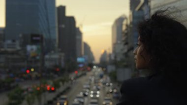Kıvırcık saçlı kadının Köprü 'de dikilip Şehre Bakışı. Şirin, Ciddi Açık Hava Kızı Sokaktaki Hayatı Düşlüyor ve Düşünüyor. İnsanlar Konsepti