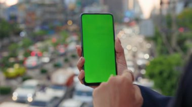 Meşgul Bir Sokağa Karşı Kadın El Tutuşunda Yeşil Ekranlı Arabalar ve Dinleme Cihazı. Akıllı Telefonu ve Chroma Anahtarı olan genç bir kız. Halk ve Teknoloji Konsepti