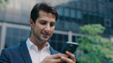 Ofisin yakınındaki Smartphone 'da Zaferi Kutlayan Resmi Takım Elbiseli Şık Patron. İnanılmaz Gülümseyen İşadamı Kazanma Anlaşması ile ilgili Sms mesajı alıyor. Kazanan İnsanlar