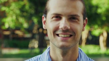 Kameraya gülümseyen genç avukat, parktaki yeşil ağaçların arka planında iyi giyimli. Yakışıklı, Üstünkörü giyinen Pozitif Profesyonel portresi. Halk ve İş Konsepti. Kapat.