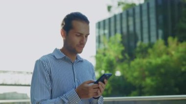 Adam işten eve yürüyor, dışarıda telefonuyla sohbet ediyor. Yakışıklı genç iş adamı patronuna Smartphone kullanarak mesaj atıyor, cep telefonuna bakıyor. Halk ve Teknoloji Konsepti