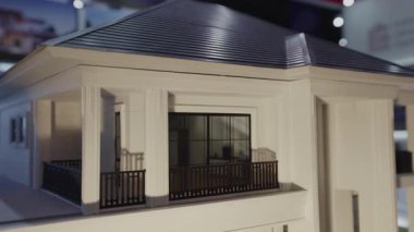 Geniş pencereleri ve loggiası olan modern evin minyatür modeli. Ev kopyalarının yer aldığı mülkiyet sergisi, konut binalarında kullanılan sürdürülebilir materyal ve akıllı sistemleri gösteriyor
