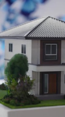 Döşeme çatılı minimalist kulübenin minyatür kopyası. Emlak fuarında cam kapı ve avluda dekoratif ağaçların yer aldığı tek aile mülkiyet modeli gösteriliyor