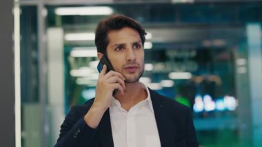 Ofiste dolaşan yakışıklı adam, akıllı telefondan ciddi konulara değiniyor. Genç Sakallı Patron Cep Telefonu ile Konuşuyor ve Ofisine Yürüyor. Halk ve Teknoloji Konsepti