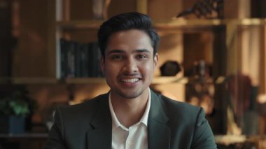 Pozitif Hintli çalışanın portresi ofiste el sallıyor ve video çağrısında başını sallıyor. Neşeli erkek menajer iş yerindeki kamera görüntülerinde patron talimatlarını dinliyor.