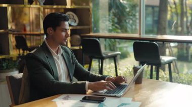 İşitme engelli Hintli işadamının portresi şirket ortamında dizüstü bilgisayarda çalışıyor. İş ortaklığında bilgisayar üzerinde kulak güçlendirici tipte çalışan bir adam.