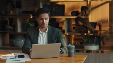 İşitme cihazı ile odaklanmış Hintli bir çalışanın portresi şirket işyerindeki laptopta çalışıyor. Özürlü girişimci masa başında bilgisayar ve çizelgelerle birlikte oturuyor