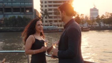 Şampanya kadehli neşeli Latin kadın portresi modern yatta yelken açan adamla konuşuyor. Mutlu İspanyol çift Tayland 'da lüks bir gemide romantik seyahatin tadını çıkarıyor. Aşk ilişkisi