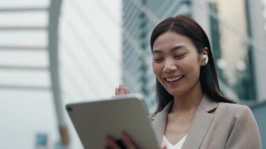 Şehir merkezindeki tablet aracılığıyla partneriyle konuşan pozitif Taylandlı bir kadının portresi. Asyalı kadın danışman müşteriyle internet üzerinden iletişim kuruyor. İş için internet hizmeti