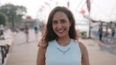Esmer Latin Amerikalı kadının portresi şehrin rıhtımında kameraya gülümsüyor. Günlük kıyafet giyen güzel İspanyol kadın şehir seti üzerinde duruyor. Gençlik yaşam tarzı
