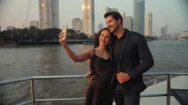 Sevecen İspanyol çiftin portresi yat güvertesinde akıllı telefondan selfie çekiyor. Mutlu Latin Amerikalı erkek ve kadın, sosyal medya yelkenli teknesi için resim çekiyorlar. Deniz yolculuğu