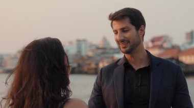 Yakışıklı Latin Amerikalı adamın portresi gün batımında deniz koyuna karşı duran kız arkadaşıyla konuşuyor. İspanyol adam Tayland 'da su seyahati sırasında partneriyle romantik bir buluşmadan hoşlanıyor.