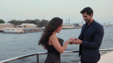 İspanyol bir adamın portresi güzel bir gelin parmak yelkenli yatında nişan yüzüğü takıyor. Mutlu Latin Amerikalı kadın ve erkek Tayland 'da tekne seyahatinde evlenme teklif ettikten sonra kucaklaşır.