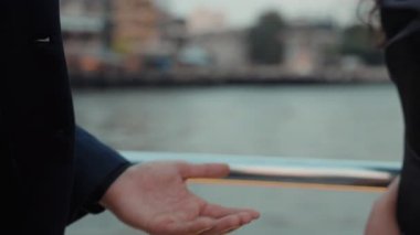 Aşık kadın ve erkeğin çiftleşme manzarası motorlu tekne güvertesinde el ele tutuşuyor. Siyah elbiseli tutkulu çift, deniz yolculuğunda romantik duygular ifade eden palmiyeler tutuyor.