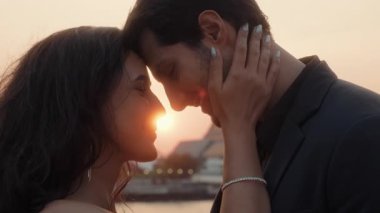Tutkulu Latin çiftin portresi günbatımında yelkenli yelkenlisinin alınlarına dokunuyor. Yeni evli İspanyol eşlerin Tayland 'da romantik tatilin keyfini çıkardıkları samimi bir an.
