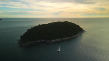 Günbatımında hava manzaralı tropikal ağaçları olan küçük ada yakınlarında lüks bir yat yelken açar. Tayland 'daki tropik cennet rahatlatıcı atmosferin tadını çıkarmak için deniz macerası sunuyor.