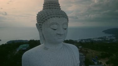 Phuket Büyük Buda heykeli bulutlu gökyüzü manzarası altında sakin okyanusa karşı. Budist tanrısı gün doğumunda sükunet ve sükunet yayar. Büyüye bağlı mimari anıt