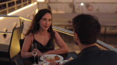 Neşeli Latin Amerikalı bir kadının portresi yatta akşam yemeği yiyen erkek arkadaşla konuşur. İspanyol kadın, akşam yemeğinde deniz gemisinde romantik bir partnerle duygularını paylaşıyor.