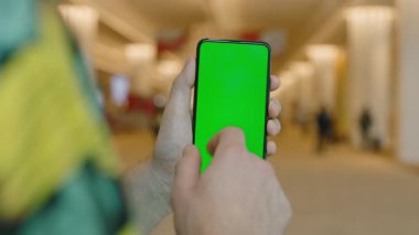 Çağdaş binadaki erkek ellerinin krom ekran ile akıllı telefona dokunuşları. Dinamik ortamda UI, uygulama veya web tasarımı için model şablonu
