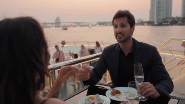 Yakışıklı sakallı Latin adamın portresi yat güvertesinde romantik bir akşam yemeğinde bir kadınla konuşuyor. İspanyol beyefendi deniz yolculuğunda sevgili bayan yelkenliyle iyi bir ruh hali paylaşıyor.