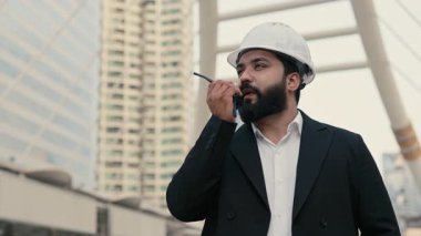 Ofis ceketli konsantre Hintli yöneticinin portresi. İnşaat alanında radyoda konuşuyor. Mühendis, kentsel alan kopyalama uzayındaki telsiz ile çalışmayı kontrol ediyor